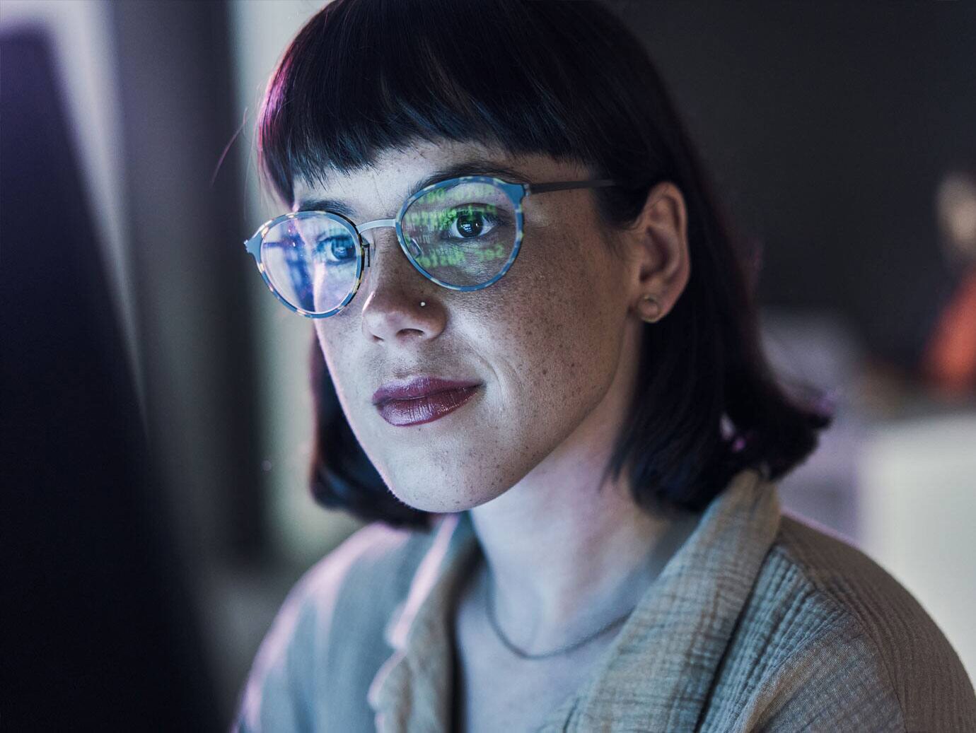 Woman wearing glasses, looking towards a screen